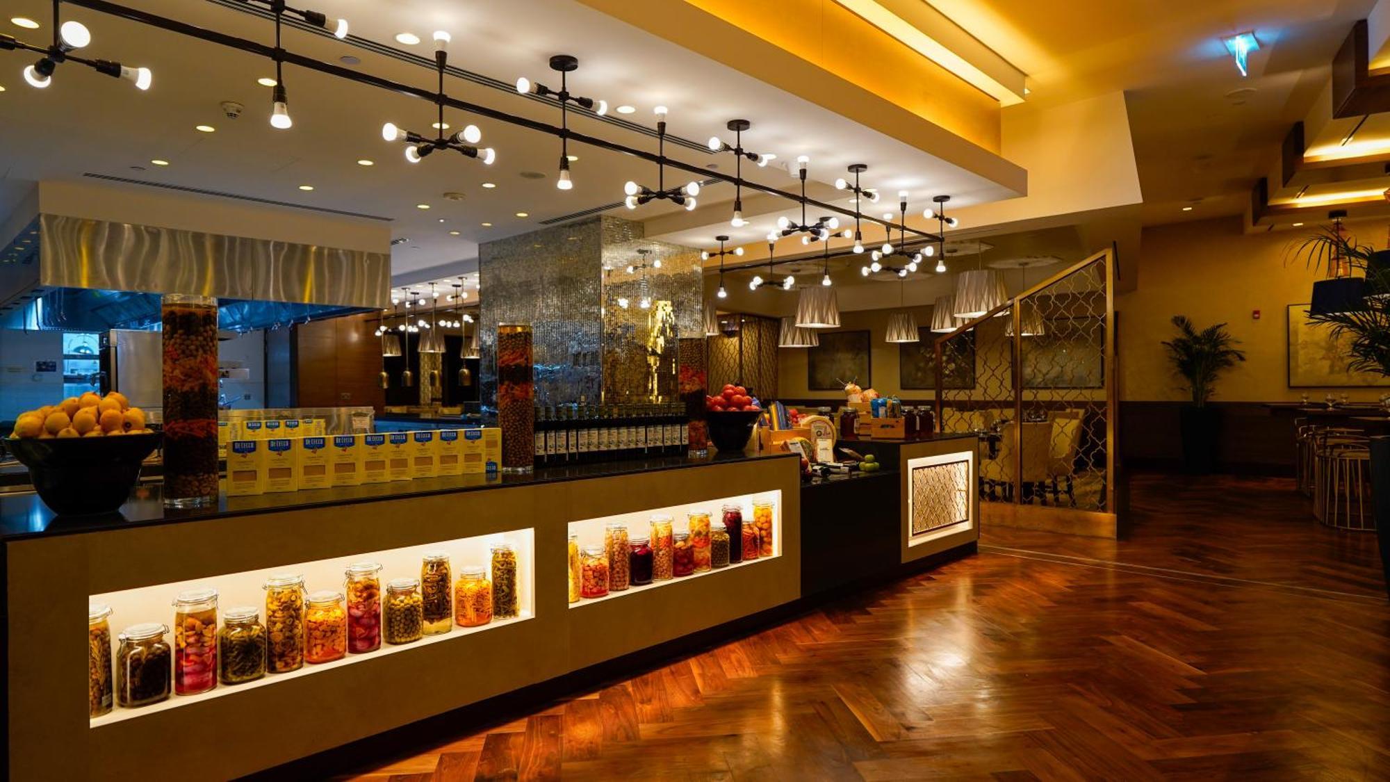 Jabal Omar Hyatt Regency Makkah Hotel Mecca Exterior photo The photo shows a stylish interior of a restaurant or café. It features a well-lit space with modern lighting fixtures hanging from the ceiling. The focal point is a counter area with jars filled with colorful ingredients or snacks, illuminated by li