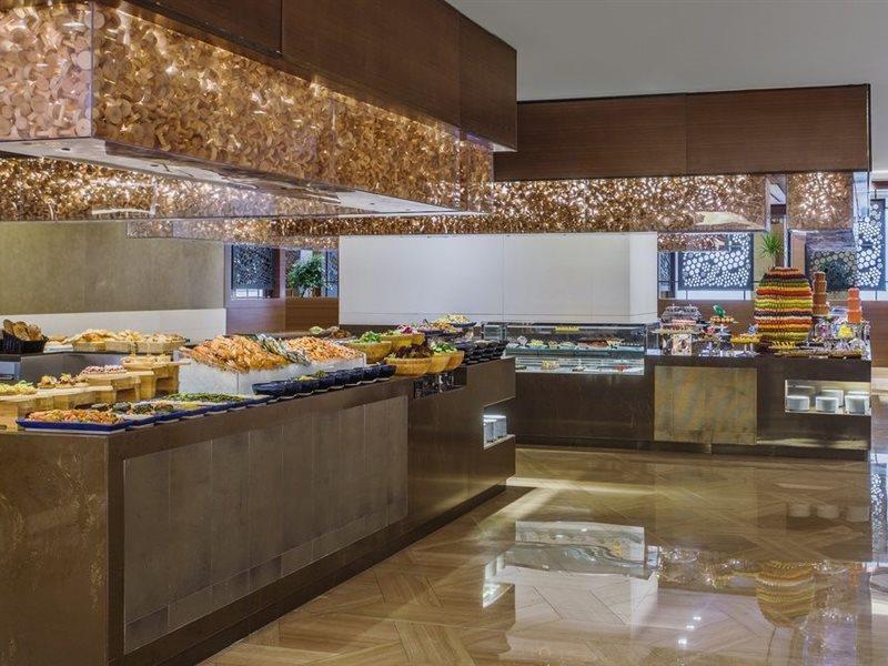 Jabal Omar Hyatt Regency Makkah Hotel Mecca Exterior photo The photo shows a stylish buffet area, likely in a restaurant or hotel. There are several food displays arranged on long tables with shiny surfaces. The buffet features a variety of items, which may include pastries, bread, and other dishes. The area
