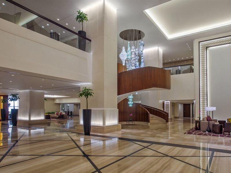 Jabal Omar Hyatt Regency Makkah Hotel Mecca Exterior photo The image shows a spacious and modern hotel lobby. It features elegant interior design with high ceilings and polished marble floors. A prominent wooden staircase with a stylish design is located in the center, leading to an upper level. There are de