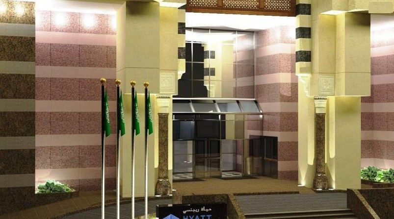 Jabal Omar Hyatt Regency Makkah Hotel Mecca Exterior photo The photo shows a building entrance decorated in a luxurious style. It features a prominent glass entrance with a modern design. In front of the entrance, there are several vertical flags, which appear to represent Saudi Arabia. The architecture incl