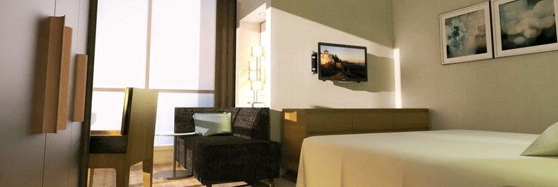 Jabal Omar Hyatt Regency Makkah Hotel Mecca Exterior photo The photo shows a modern hotel room or living space featuring a small seating area. On the left, there is a dark-colored couch and a glass side table. Across from the couch, mounted on the wall, is a flat-screen television. The room has light-colored
