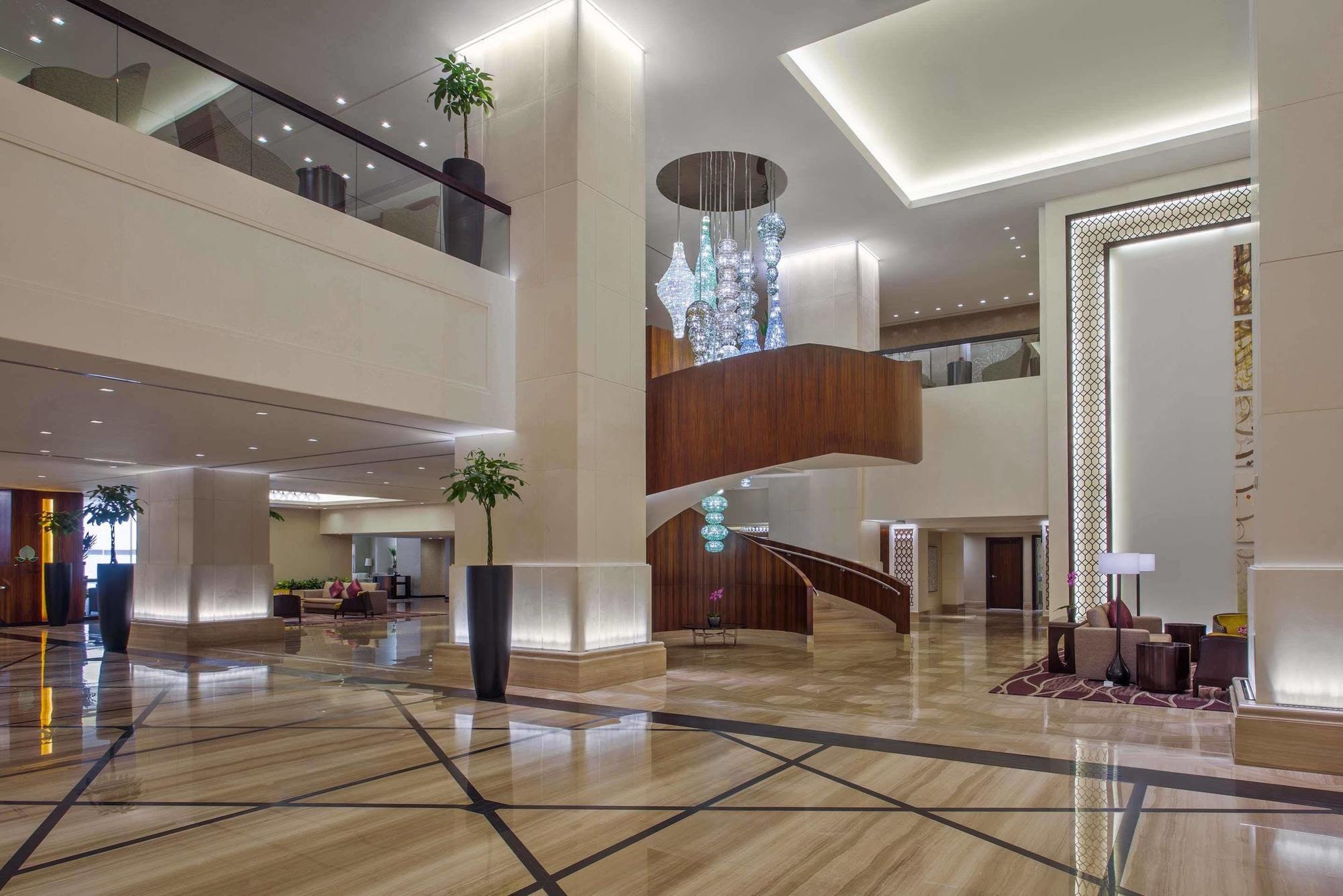 Jabal Omar Hyatt Regency Makkah Hotel Mecca Exterior photo The photo shows a spacious and elegantly designed hotel lobby. The interior features large marble flooring with a geometric pattern, complemented by modern lighting fixtures. A grand staircase with wooden accents is prominent in the center, leading t