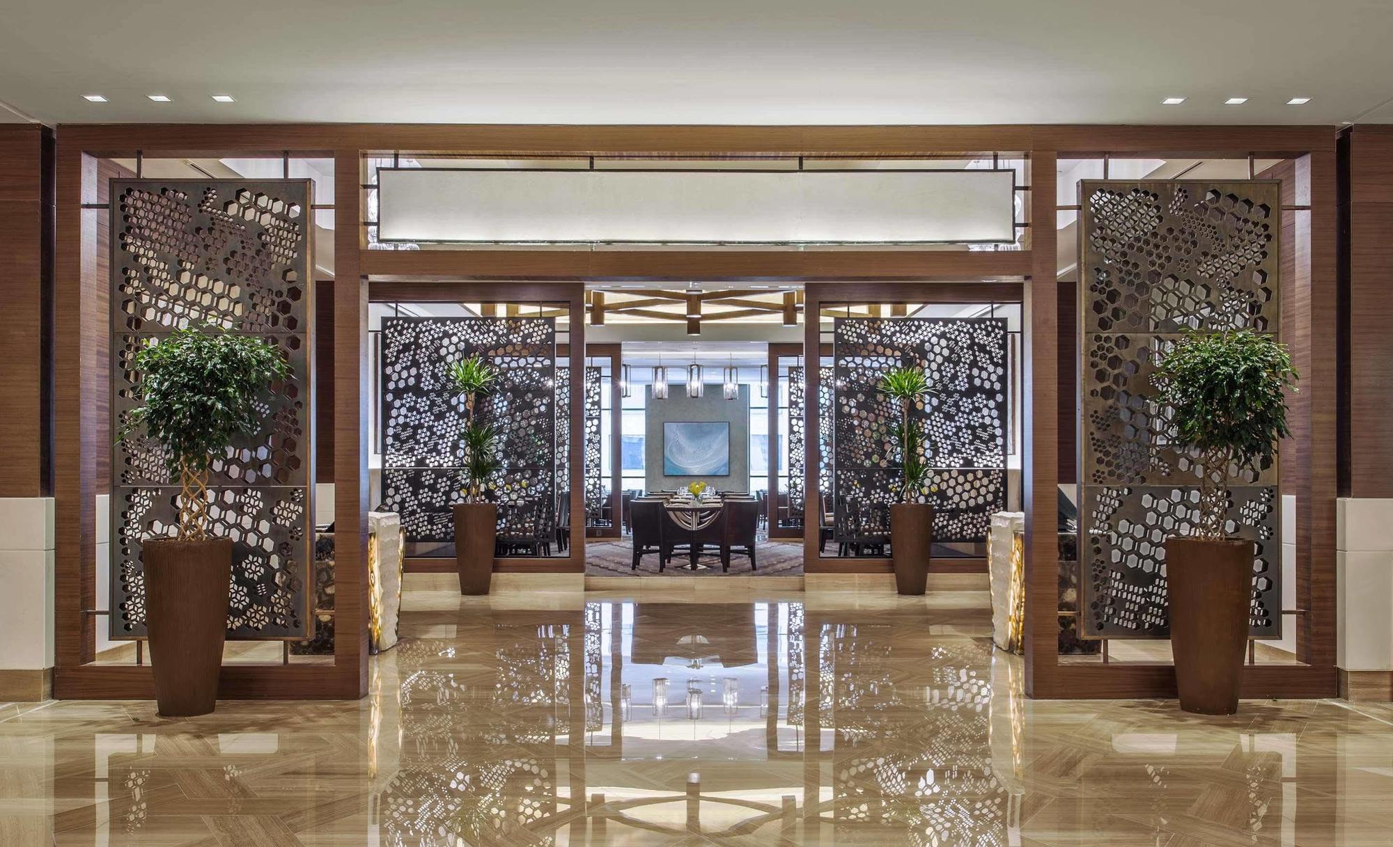 Jabal Omar Hyatt Regency Makkah Hotel Mecca Exterior photo The image shows an elegant interior space, likely the lobby or entrance of a luxurious hotel or restaurant. The area features decorative partitions with intricate designs, framed by wooden structures. These partitions create a sense of separation whi