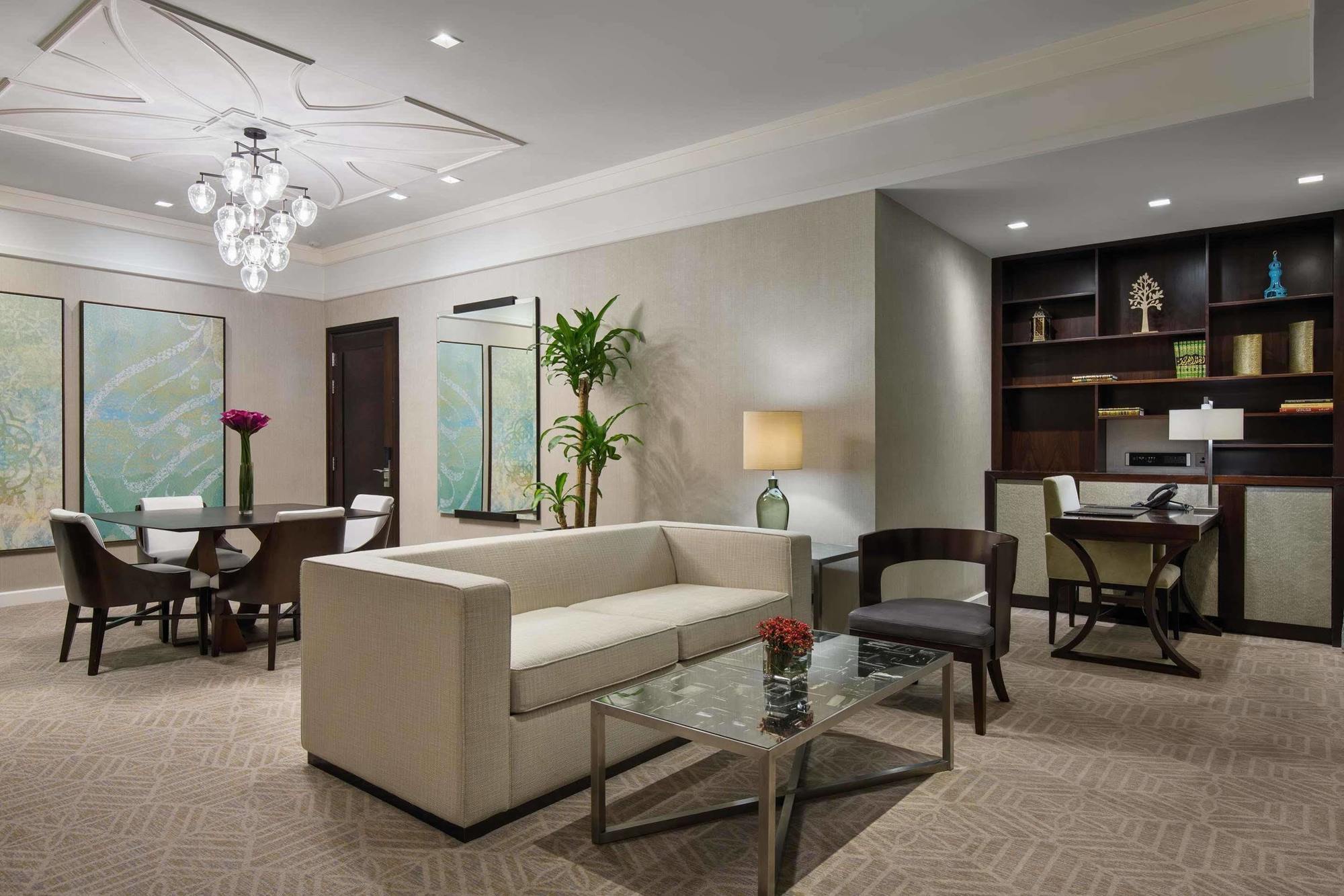 Jabal Omar Hyatt Regency Makkah Hotel Mecca Exterior photo The image shows a contemporary living space that includes a light-colored sofa and a glass coffee table. In the background, there is a dining area with a round table and chairs, along with framed artwork on the walls. A potted plant adds a touch of g