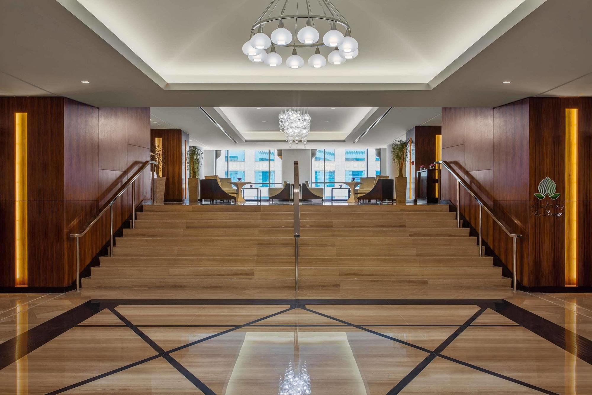 Jabal Omar Hyatt Regency Makkah Hotel Mecca Exterior photo The photo depicts a modern and elegant lobby area. There is a wide staircase made of wood that leads up to another level, flanked by stylish seating on both sides. The lobby features a combination of wooden and marble flooring, with a geometric patte
