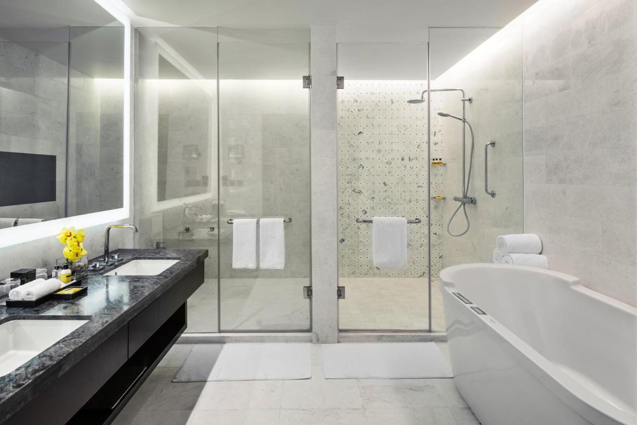 Jabal Omar Hyatt Regency Makkah Hotel Mecca Exterior photo The photo shows a modern bathroom with a sleek design. It features a glass shower enclosure with a rainfall showerhead and a stylish bathtub. The floor and walls have a light-colored stone or tile finish, giving a clean and minimalist look. There's a
