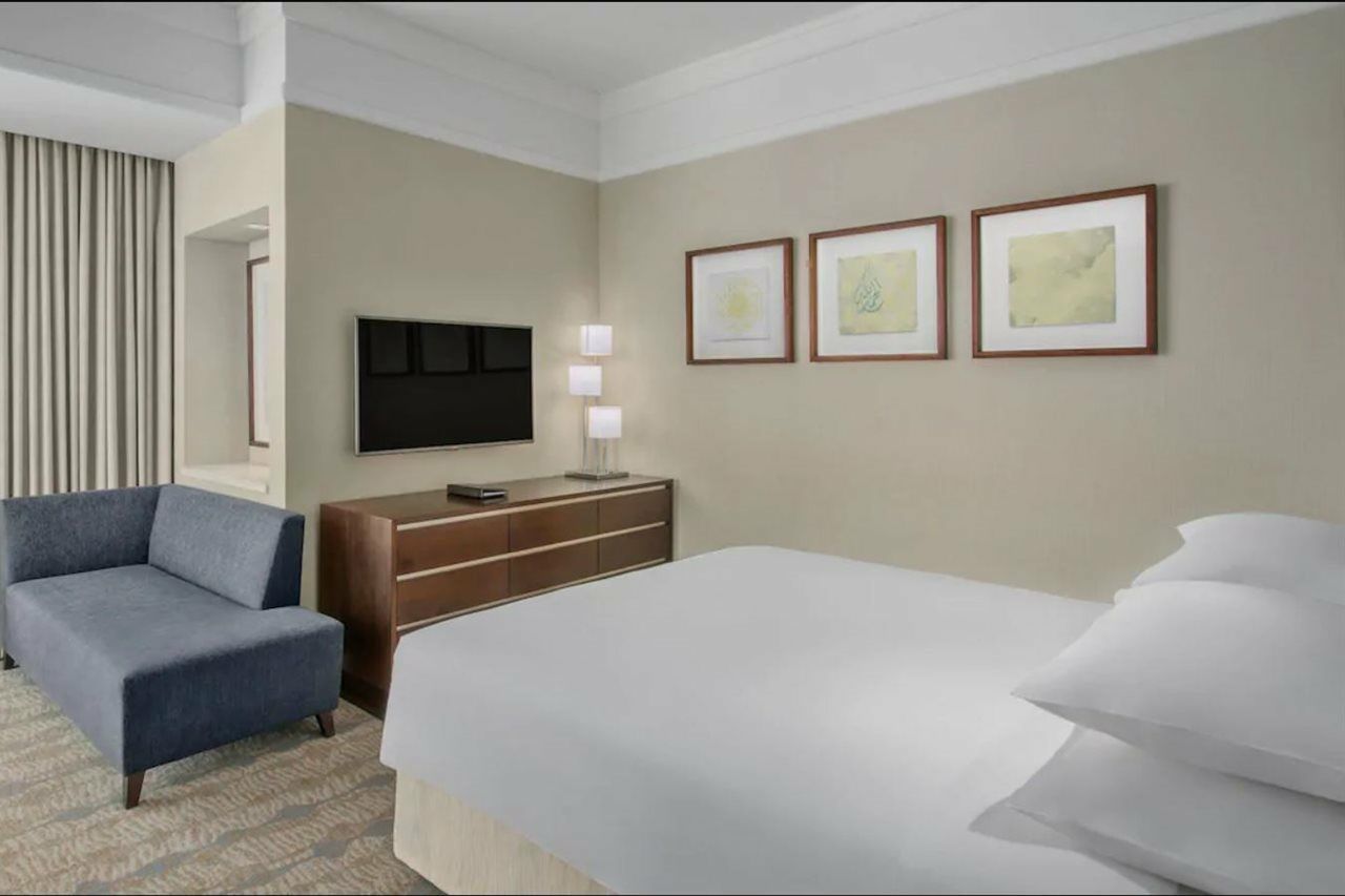 Jabal Omar Hyatt Regency Makkah Hotel Mecca Exterior photo The photo shows a modern hotel room. It features a neatly made bed with white linens and multiple pillows. On the wall opposite the bed, there is a flat-screen television mounted, along with a modern wooden dresser. Above the dresser, three framed ar